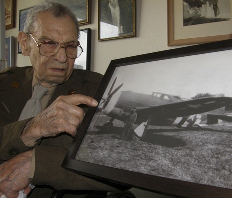 World War II veteran Paul V. Myers points to a picture of himself in front of a P-47 Thunderbolt.