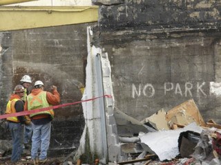 Demolition crews survey the tavern block during work Wednesday. The former row of taverns is being demolished to make way for downtown development.