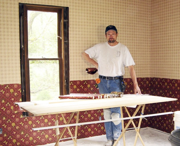 Mike Brandhagen applied new wallpaper to the farmhouse parlor as part of the restoration efforts.