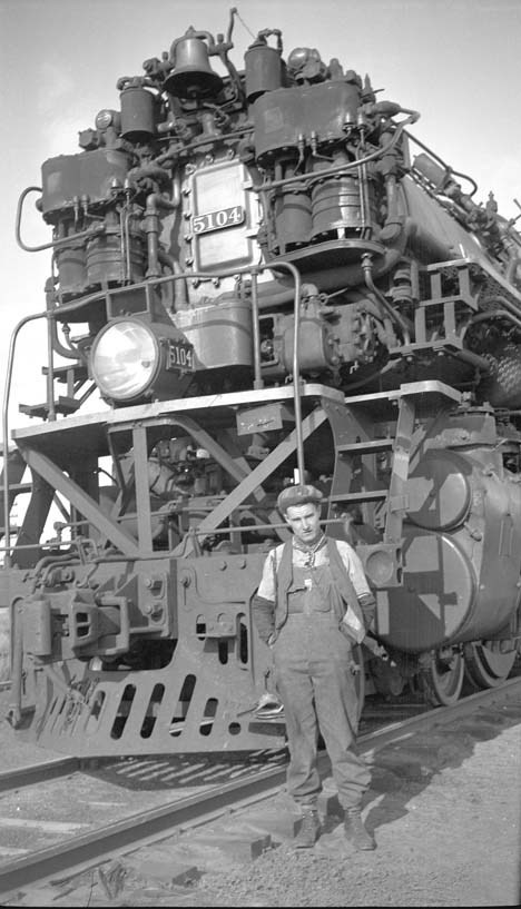 Brakeman Warren McGee stands in front of a steam locomotive
