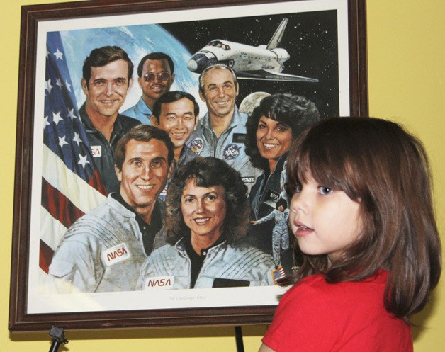 Nevaeh Colvert of Lori Adam's kindergarten class passes by a painting of the fallen Challenger crew following a school-wide assembly at Dick Scobee Elementary last Friday. Auburn's Scobee