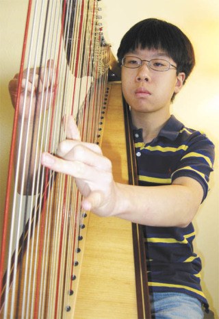 Timmy Kosaka plays his 47-string harp at his Auburn home. Timmy