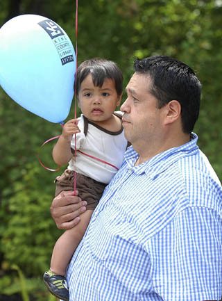 Muckleshoot tribal councilmember John Daniels Jr. holds his son John III at the opening of the new Muckleshoot Library.