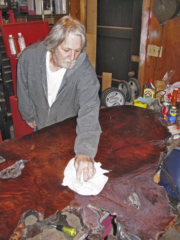 Michael Hall polishes one of the hand-crafted tables at his shop.