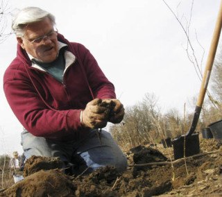 Dick Vasel plants a tree on the reconstructed Fenster levee.