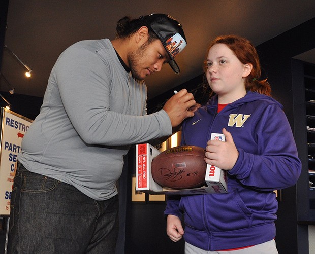 NFL defensive lineman Danny Shelton signs 12-year-old Emma McLaughlin’s jacket and gives her an autographed football during an appearance at Way Scarff Ford on Saturday.