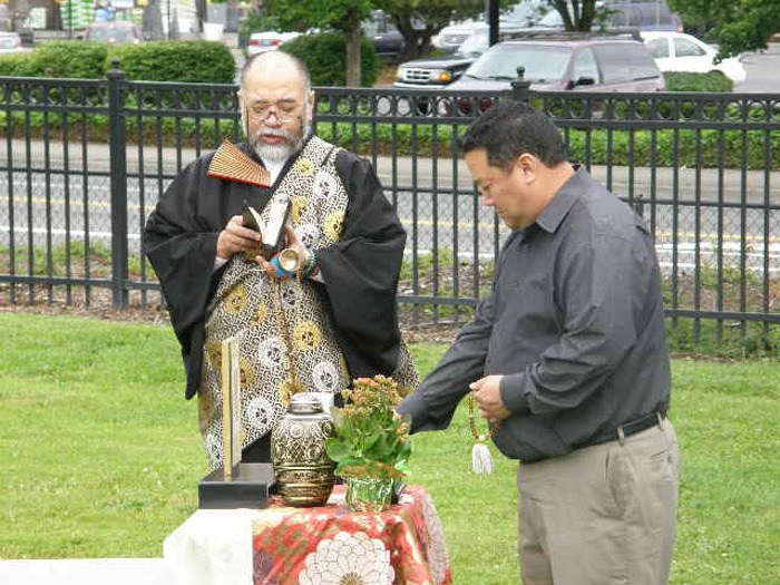 Reverend Kakei Nakagawa and a mourner pay their respects to Mae and Maki Yamada at Pioneer Cemetery.