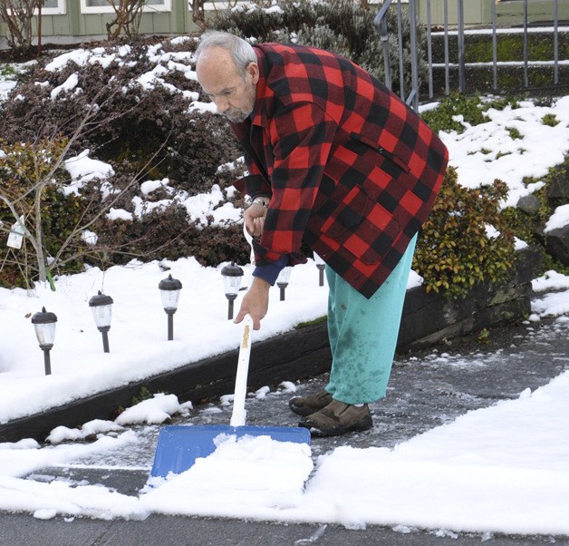 Bill Burchell takes time to shovel snow from his driveway on Tuesday.