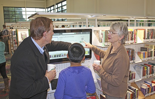 King County Councilmember Pete von Reichbauer and King County Library System Trustee Robin McClelland show a young patron how to use the new touch-screen service at the King County Library on 320th Street in Federal Way.