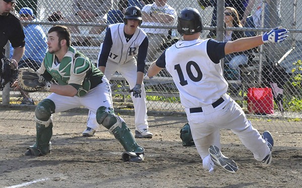 Auburn Riverside's Sam Gocken looks on as teammate Kevin Thomson tries to beat the throw to catcher Auburn catcher Connor McCoy. The Ravens topped the Trojans 6-0 in the contest.