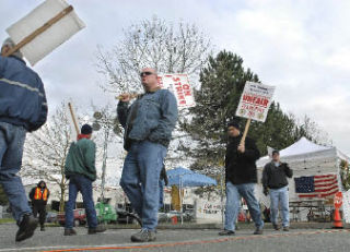 Members of Teamsters Union Local 763 picket outside the Oak Harbor Freight Lines’ yard. The strike has stretched nearly 11 weeks for truckers.