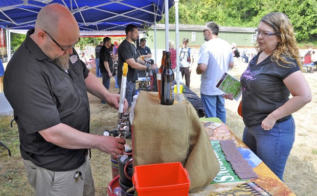 Erik Carels gives Toni Gates a taste of beer during the Hops & Crops Brew Festival at Mary Olson Farm last Saturday. The event raised $7