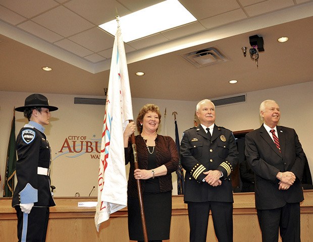 Passing it on: Mayor Nancy Backus holds the City flag after being sworn in as mayor during ceremonies at City Hall on Monday. From left are Police Officer Francesca Nix