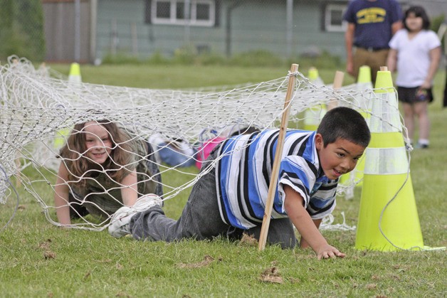 Second-grader Jaysovann Man leads Natalie Potter in a crawl under a net during the Dick Scobee Elementary Relay Recess
