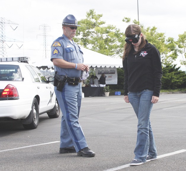 Anna Fairchuk takes a sobriety test wearing impairment goggles as WSP Sgt. Ken Denton observes during the Ford Driving Skills for Life event at Emerald Downs.