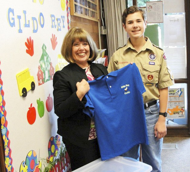 Boy Scout Adam Berry recently delivered new choir uniforms to Gildo Rey Elementary School and principal Robin Logan.