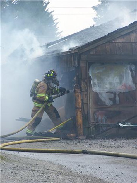 A VRFA firefighter goes to work in trying to contain a detached garage fire at the 300 block of “E” Street Southeast in Auburn on June 4. Nick Wilson
