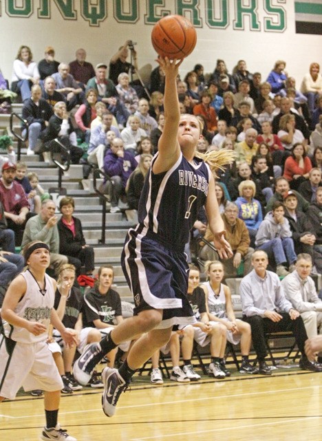 Mercedes Wetmore darts past Conqueror guard Kylie Huerta for a layup at Kentwood on Tuesday. Wetmore led the Ravens with 19 points.