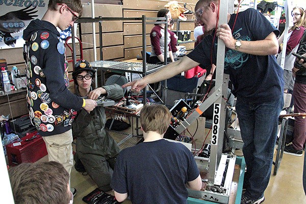 Members of Auburn Riverside's RAVE Team 5683 First Robotics work on their robot at the Auburn district qualifying event.