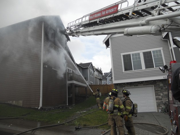 Firefighters work to douse a house fire in the 5000 block of Elliott Court Southeast in Lakeland Hills on Wednesday.