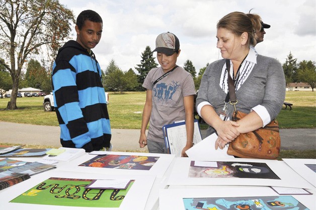 Artist Robert Williams shows is work to case managers Khanie Ha and Mary Frenzel-Brock during the Urban ArtWorks celebration and arts sale last week at Les Gove Park.