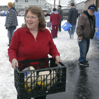 Debbie Christian carries in some frozen turkeys for the Holiday Basket Giveaway at Holy Family Catholic Church on Tuesday. Christian