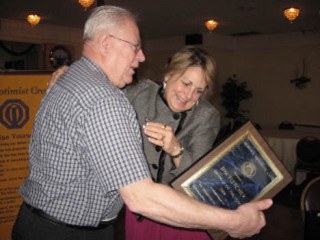 Jim Fletcher accepts the top volunteer award from Optimists president Pamela Schmidt.