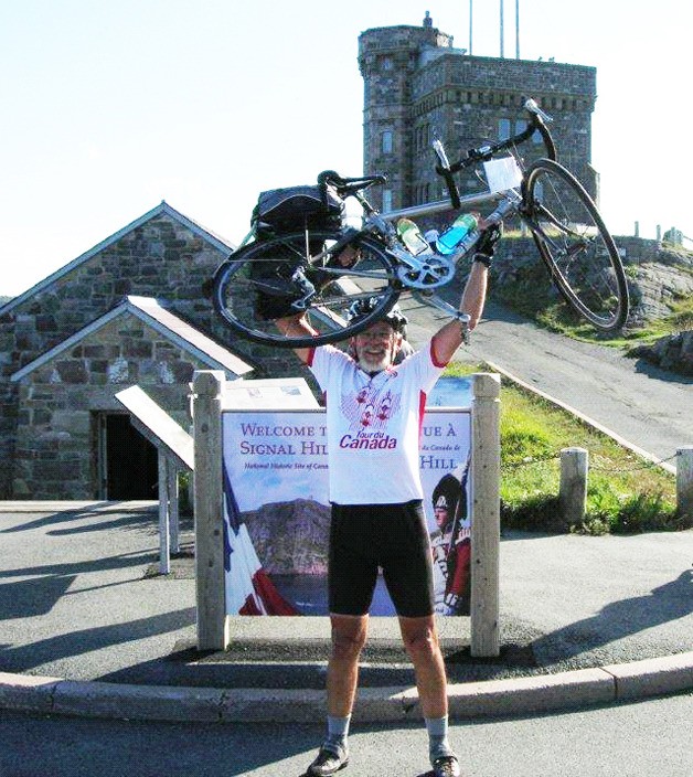 Jim Hamilton hoists his bicycle in Newfoundland after completing a coast-to-coast tour of Canada.