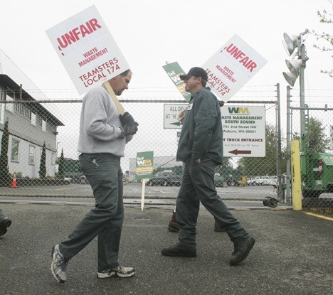 Waste Management truck drives walk the picket line at the Auburn Waste Management South Sound site Wednesday. Workers belonging to Teamsters Union Local 174 claim their employer