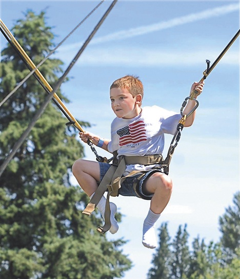 Blake Deshler swings on a trampoline apparatus at Les Gove Park during the Fourth of July festivities. The celebration at the park drew thousands of people