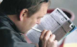 John Paul of Olympia pours over the race program during opening weekend at Emerald Downs.