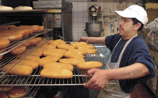 Buntheang Heng puts some freshly fried bars in the cooling rack at his Donut & Muffin Shop in downtown Auburn.