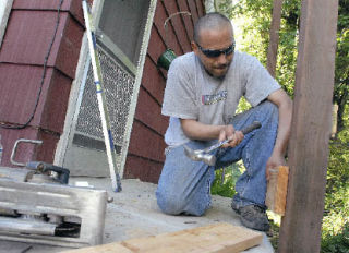 Rodrigo Lara works on the wheelchair ramp for Penelope Popovich. A work crew from Centex Homes and two of their subcontractors