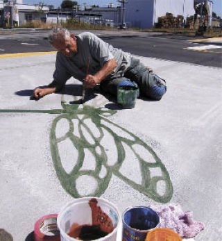 Tom Askman applies a stroke of fresh paint to a dragonfly that was etched into the sidewalk along West Main Street.