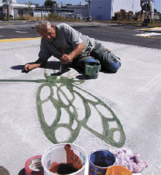 Tom Askman applies a stroke of fresh paint to a dragonfly that was etched into the sidewalk along West Main Street.