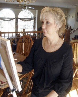 Wendy Ray works on a still life painting in the dining room of her Lakeland Hills home. Ray’s work is featured at the Auburn Avenue Theater from now until April 28.