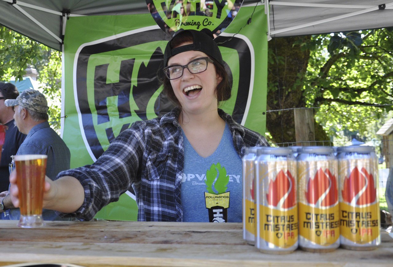 Erika Sherman from Hop Valley Brewing serves up a beer at the seventh annual Hops & Crops Festival at Mary Olson Farm last Saturday. RACHEL CIAMPI