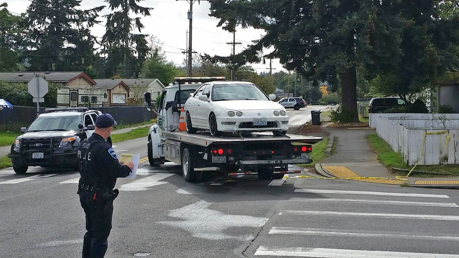 An Auburn Police officer halts traffic as a tow truck hauls away the car in which a 17-year-old boy was killed early Friday morning in south Auburn. ROBERT WHALE