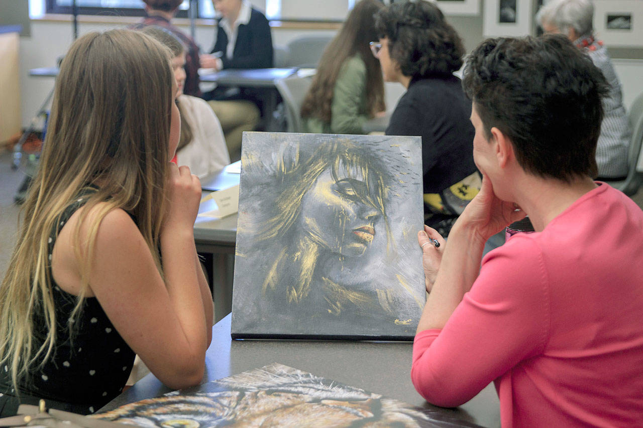 Monica Tolas, of Interurban Center for the Arts, right, studies the artwork of student Kristine Kravchishin during Green River College’s recent Portfolio Review. COURTESY PHOTO, Jaclynn Board