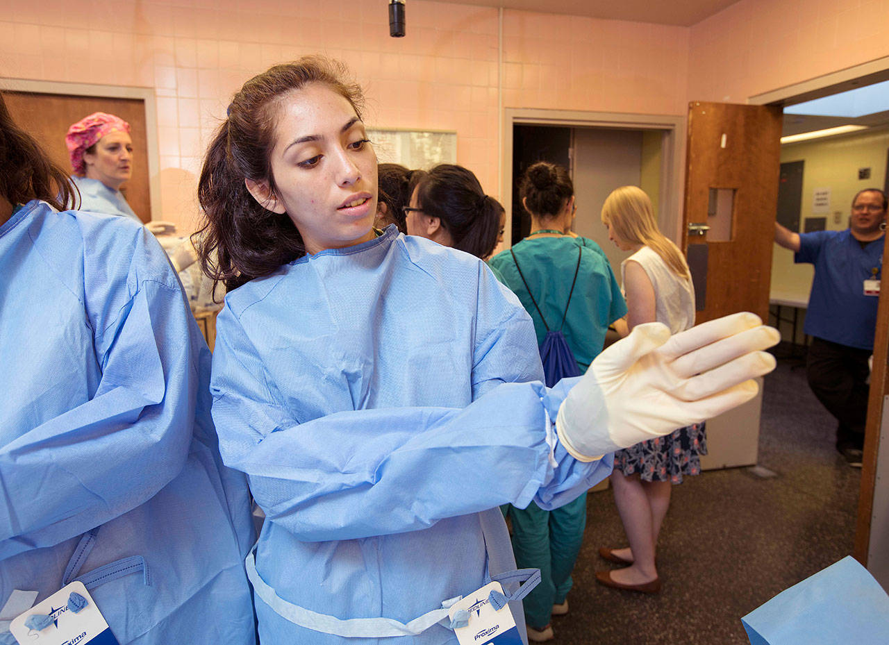 Genevieve Tipton, of Auburn, puts on her gown and gloves at Nurse Camp last week. COURTESY PHOTO, Patrick Hagerty