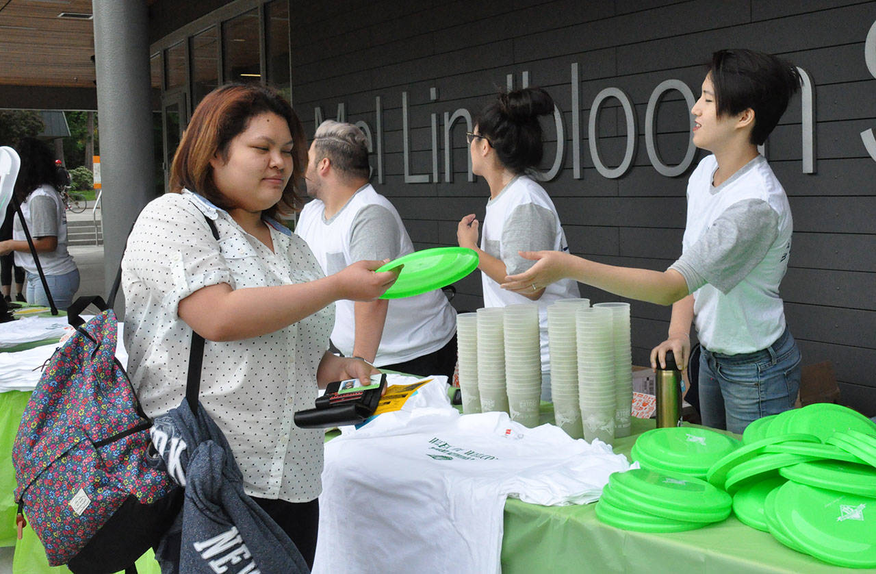 Joy Chang, right, hands a student a frisbee during a Welcome Week giveaway on Monday. HEIDI SANDERS, Kent Reporter