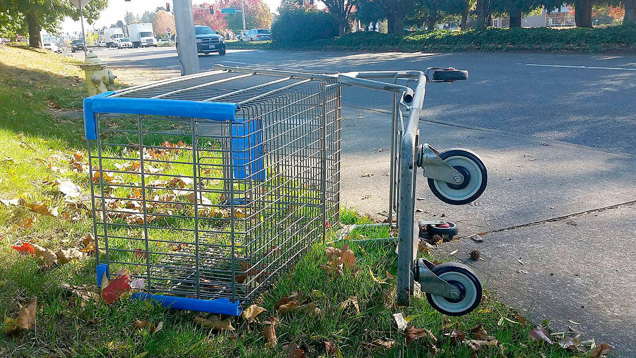 Traffic zips by an abandoned shopping cart lying upside-down along 15th Street Southwest on Tuesday morning. ROBERT WHALE, Auburn Reporter