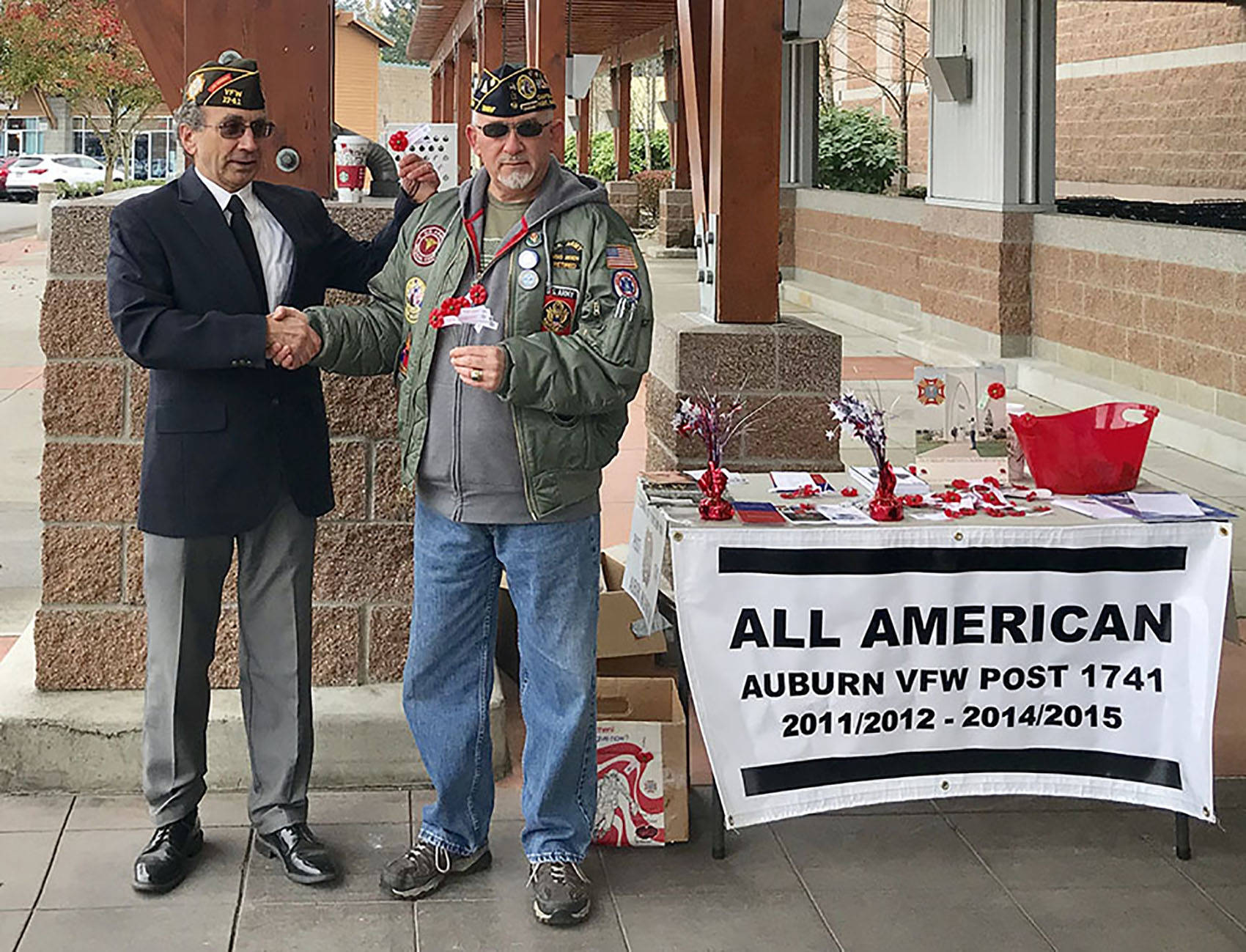 Michael Sepal, U.S. Army retired and life member and Officer of the Day, VFW Post 1741, Auburn, greets and presents Chriss Moen, Army retired and life member of Disabled American Veterans, Chapter A-One 33, Kent, with ‘buddy’ poppies and thanks him for his charitable donation. COURTESY PHOTO