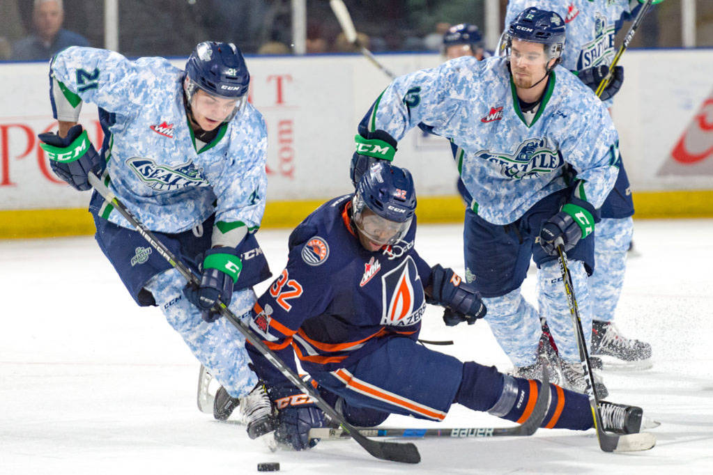 The Thunderbirds’ Matthew Wedman, left, and Blake Bargar battle the Blazers’ Jermaine Loewen for the puck during WHL play Saturday night. COURTESY PHOTO, Brian Liesse, T-Birds