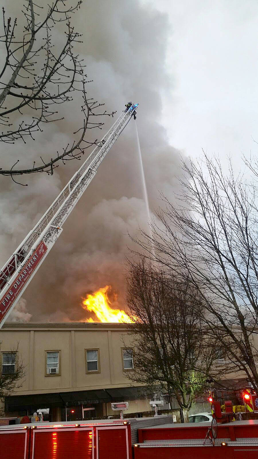 With the aid of ladder trucks, local firefighters try to contain a massive blaze in downtown Auburn late Tuesday afternoon. ROBERT WHALE, Auburn Reporter