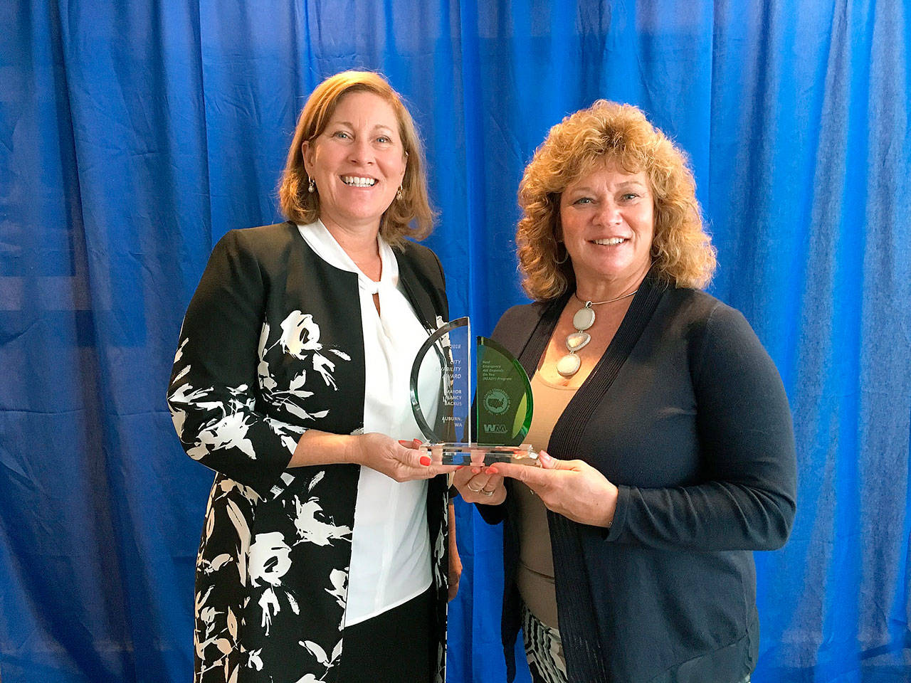 Susan Moulton, senior corporate director of Public Sector Solutions for Waste Management, left, presents the City Livability Award to Mayor Nancy Backus. COURTESY PHOTO