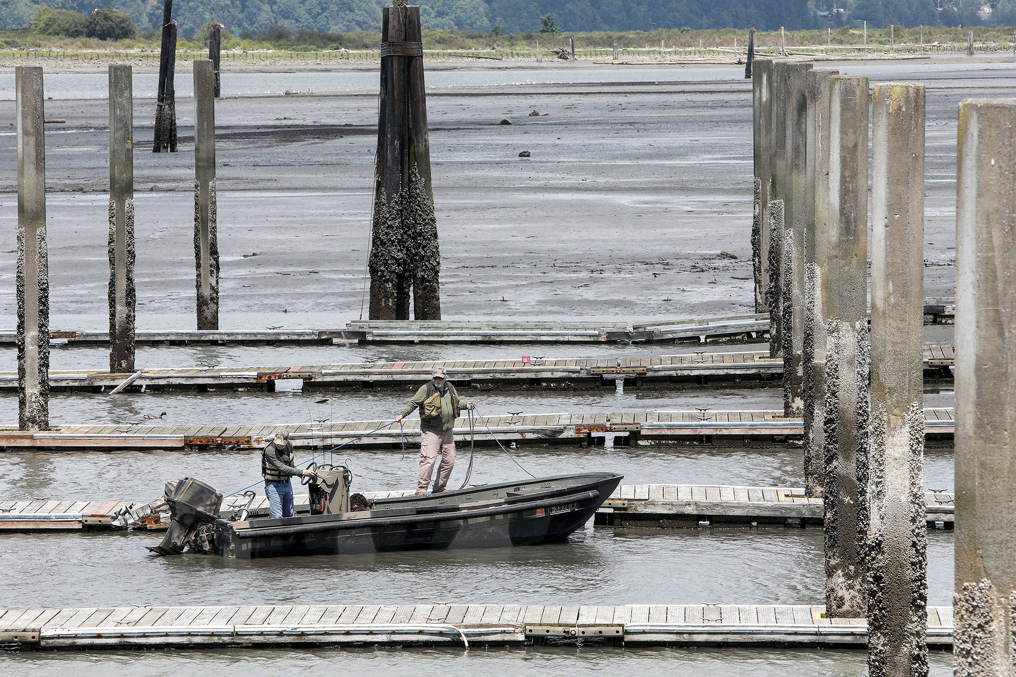 Ron Buckner (right) and Jim Fetzer struggle to make it back to the 10th Street Boat Launch during one of the lowest tides of the year. (Lizz Giordano / The Herald)