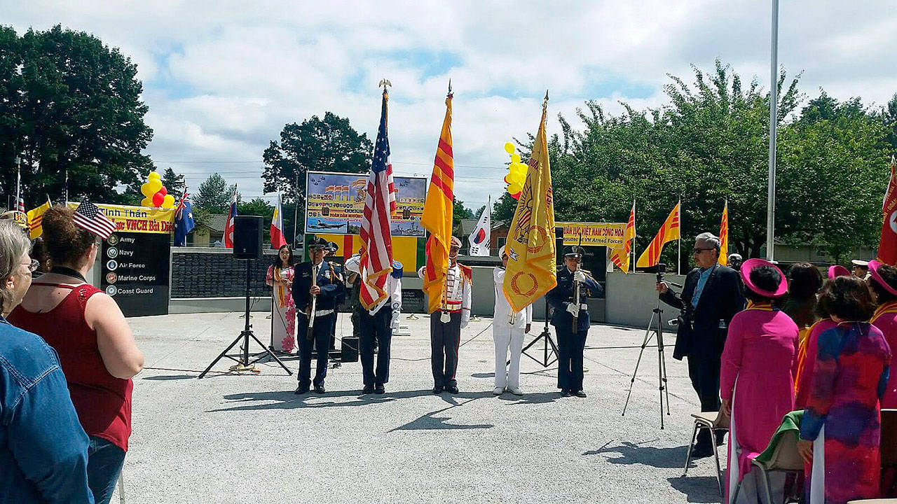 Flags of the two nations that fought side-by-side in the Vietnam War look down upon the dedication of the joint American-Vietnamese Memorial at Les Gove Park lsdy Saturday morning. ROBERT WHALE, Auburn Reporter