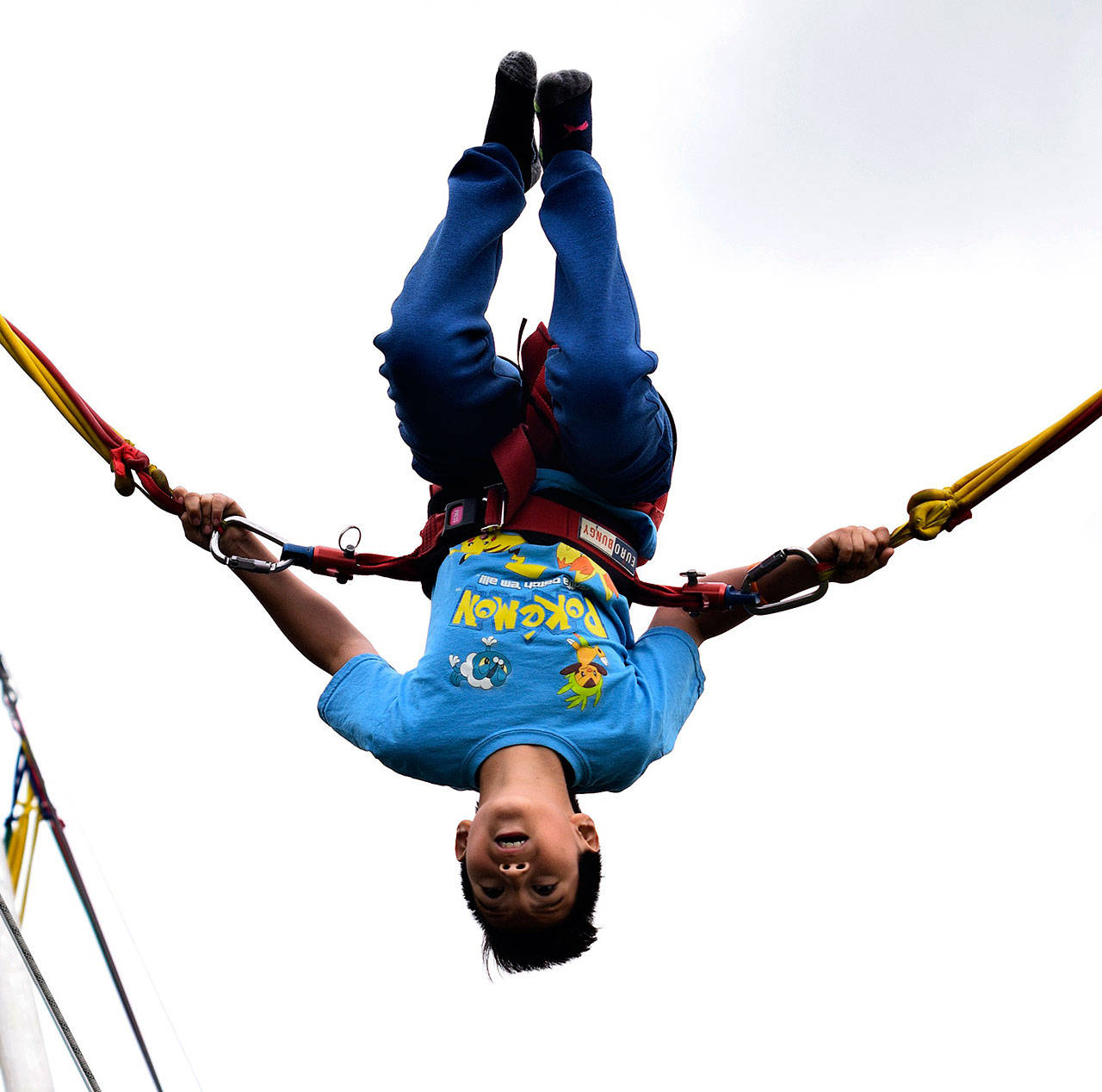 Christian Cordova, 10, does flips on the bungee trampoline during Kids Day at Les Gove Park. RACHEL CIAMPI, Auburn Reporter