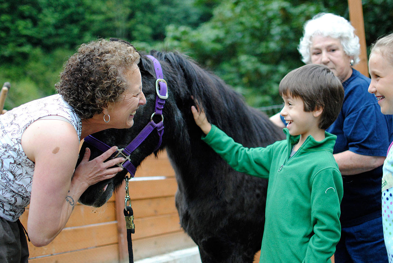 White River Valley Museum Director Patricia Cosgrove shares a happy moment with a boy and a donkey at Mary Olson Farm. COURTESY PHOTO